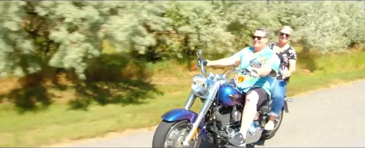 Robert and Teri riding together along a tree-lined road